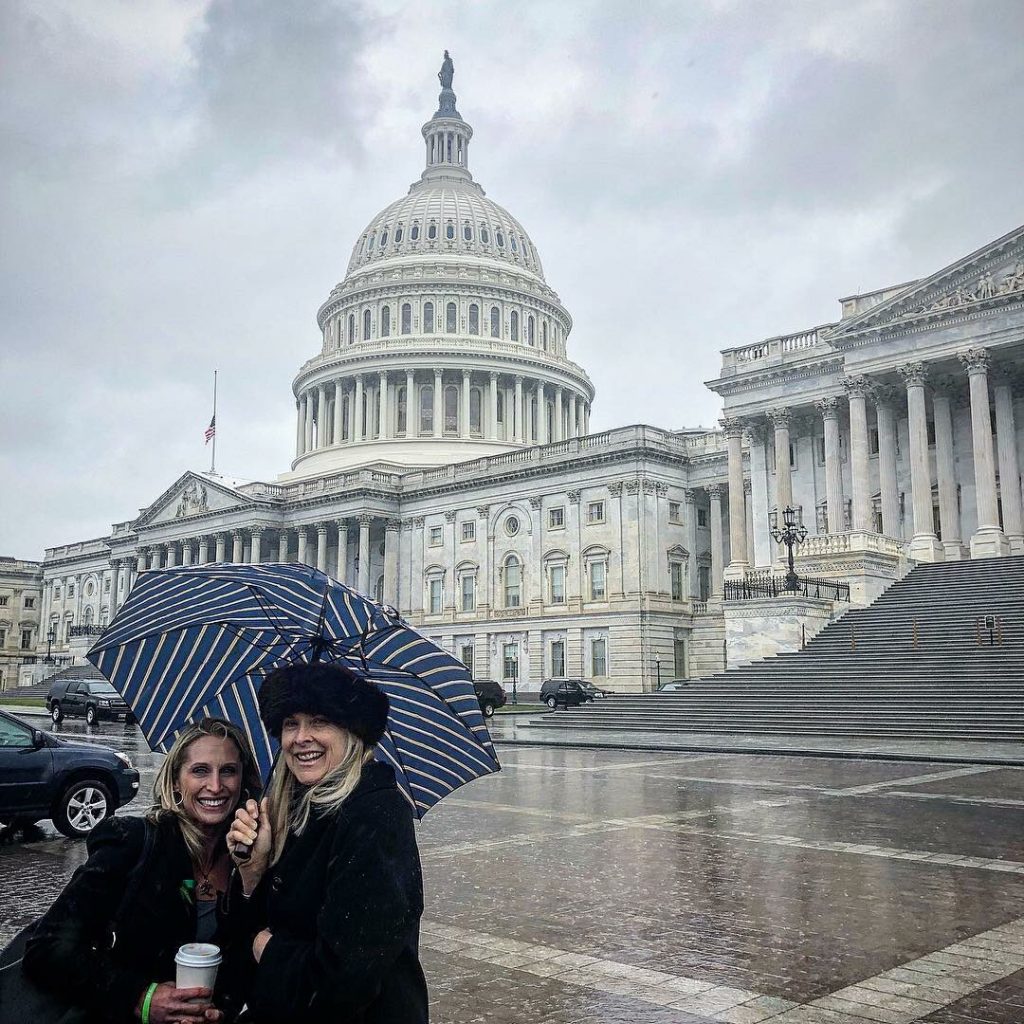 Two Advocates for Brain Injury Awareness Day under an Umbrella on A Rainy Day on Capitol Hill